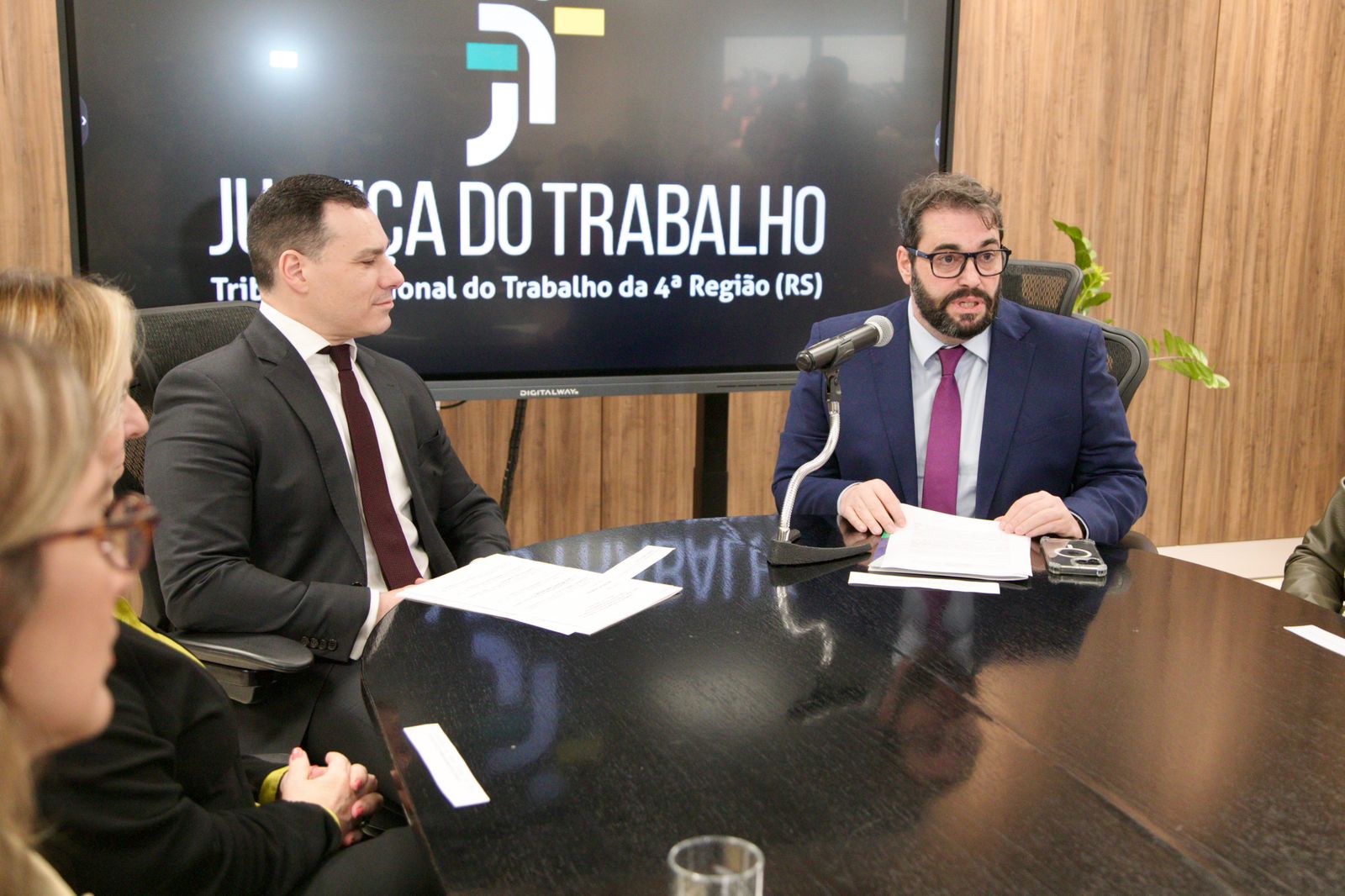 A foto mostra Alexandre e Eduardo lado a lado. Alexandre façando ao microfone.